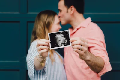 Happy couple sharing pregnancy announcement with ultrasound photo.